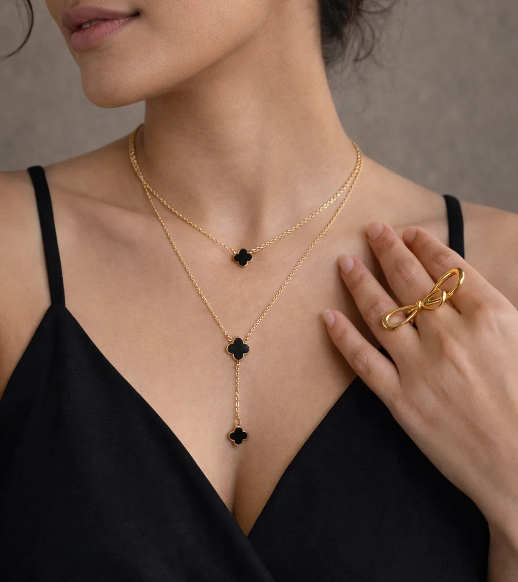 Gold-tone layered necklace with black clover charms, three drop pieces