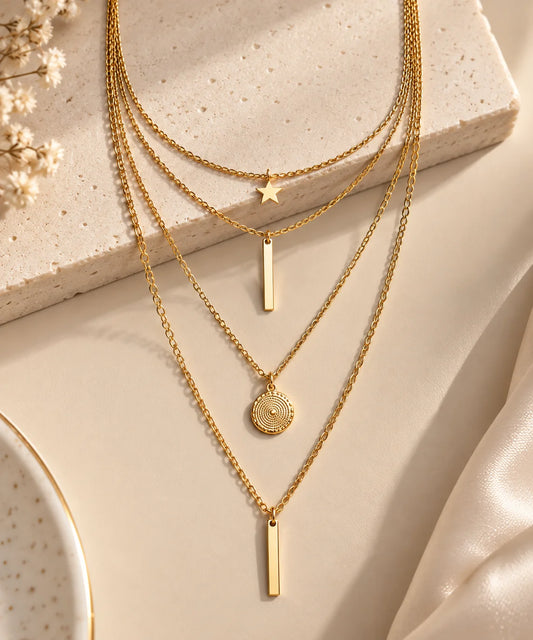 Gold-tone close-up layered necklace with star, two bar pendants, and round disc charm
