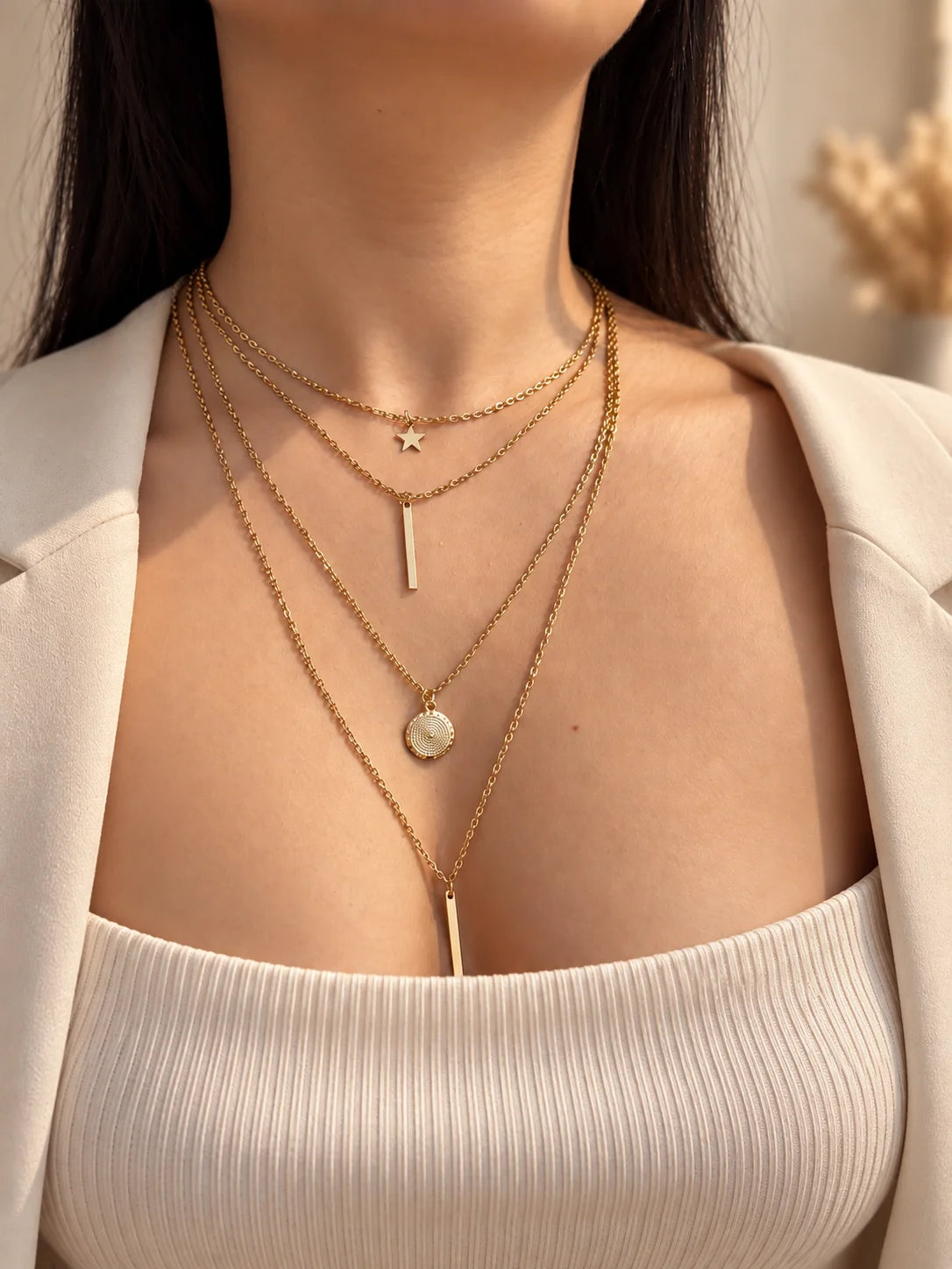 Gold-tone layered necklace with star charm, vertical bar, and round coin pendant