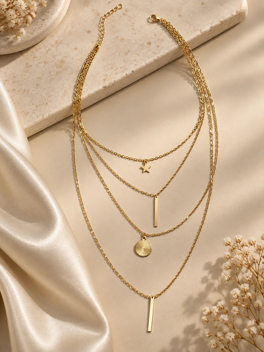 Gold-tone triple-layer necklace with star charm, bar charm, and round coin pendant