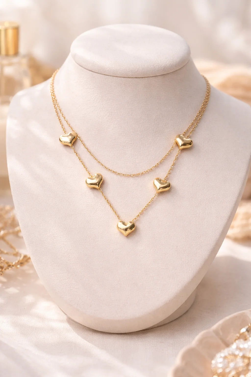 Gold-tone layered necklace with three heart charms on delicate chains