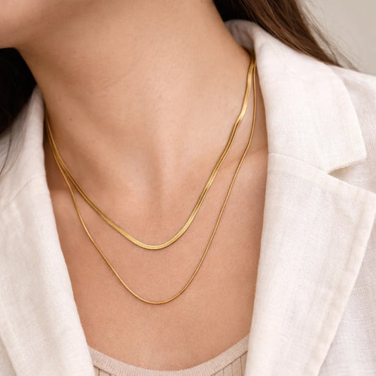 Layered snake chain necklaces worn on neckline, two gold-tone lengths