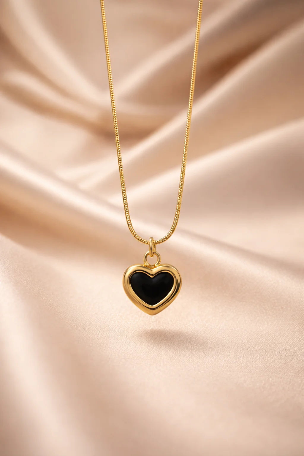 Gold heart pendant necklace with black center on a fine chain