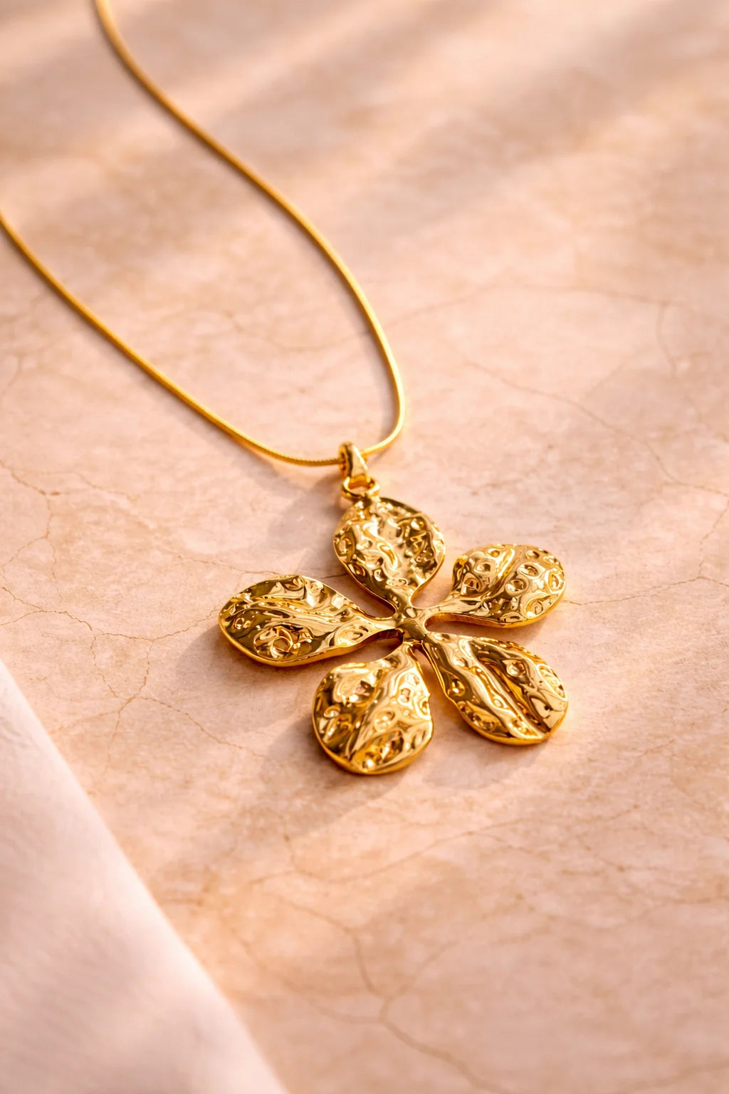 Gold-tone flower pendant necklace with textured five-petal charm on thin chain