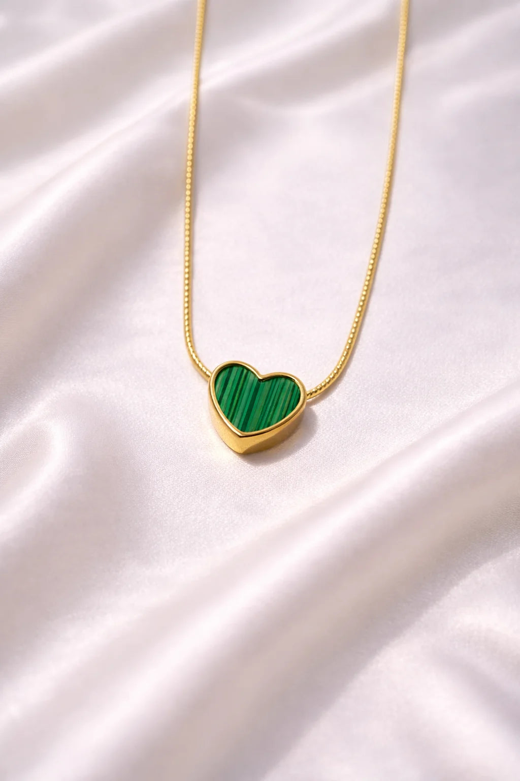 Gold necklace with green striped heart pendant