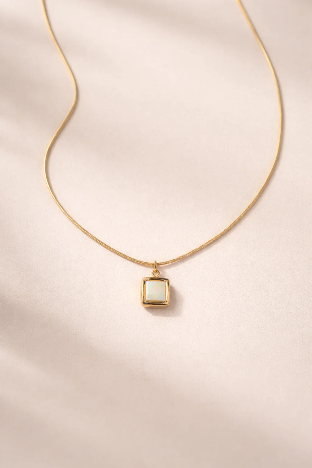 Gold-tone square pendant necklace with light stone on thin chain