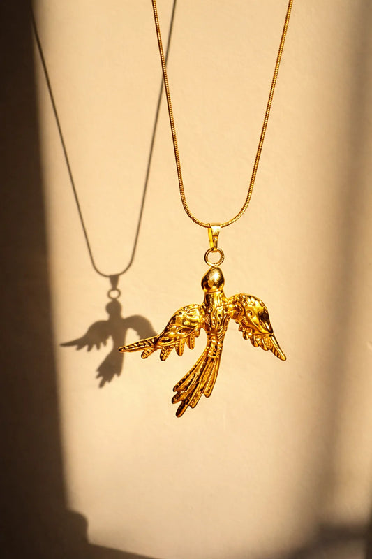 Gold bird pendant necklace with a long chain and detailed phoenix charm, gold clasp