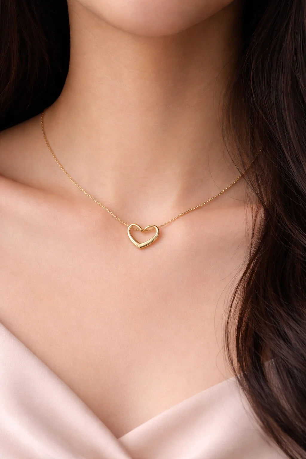 Gold outlined heart pendant necklace worn at the neckline on a thin chain