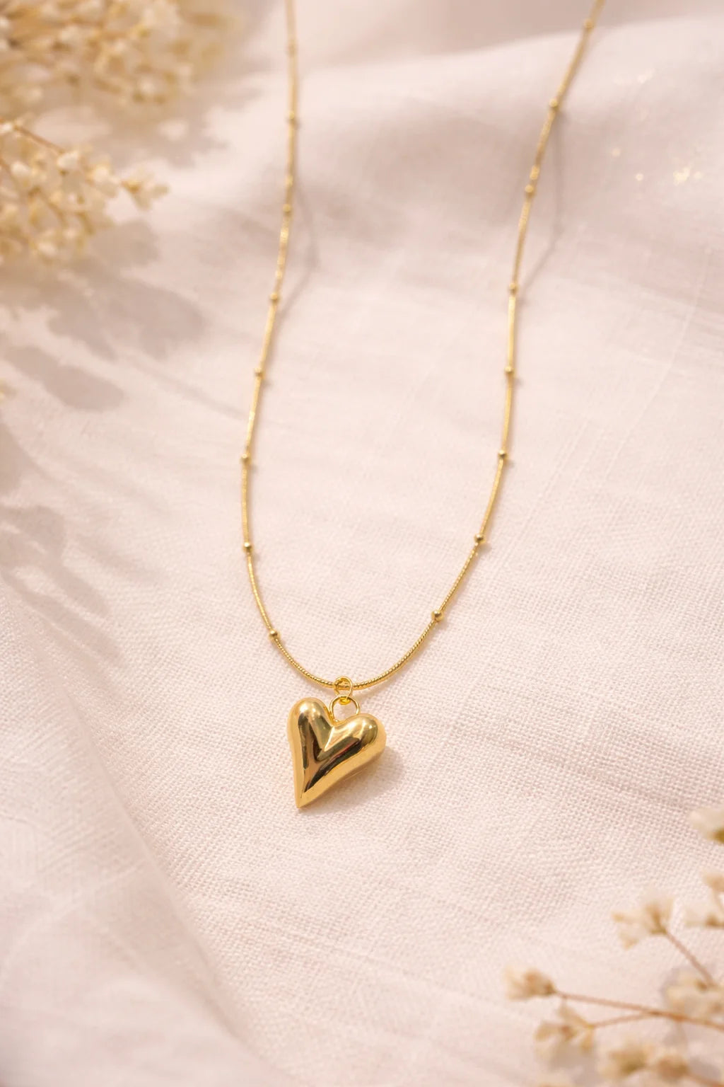 Gold heart pendant necklace with thin chain and small heart charm at center
