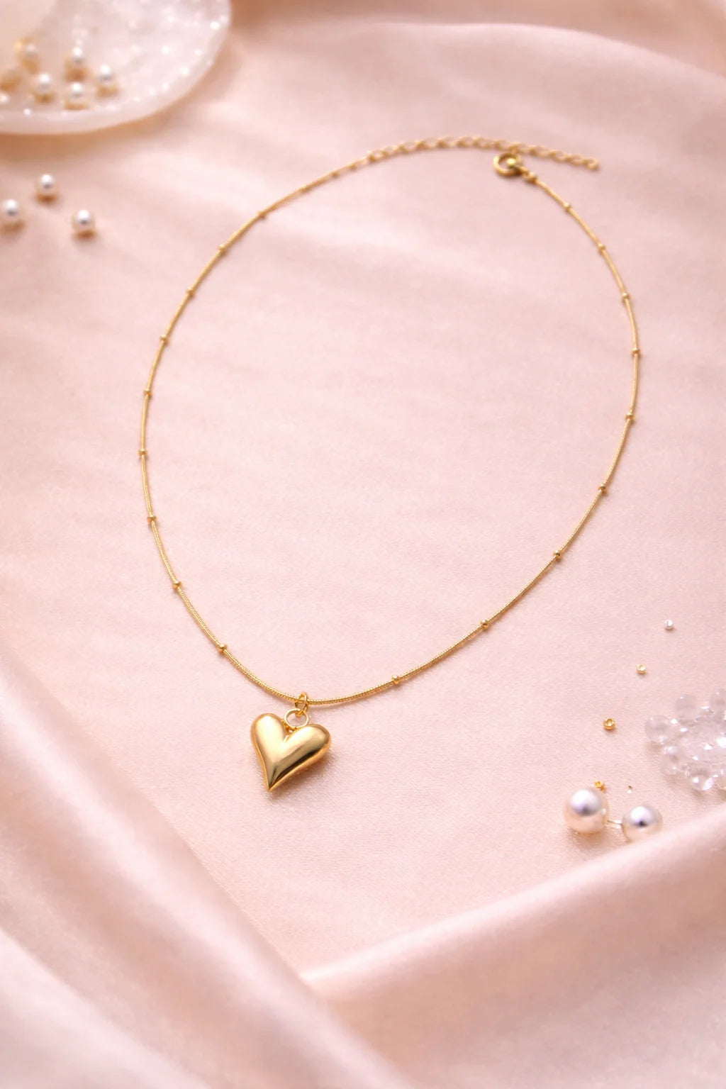 Gold heart charm necklace with thin chain and small heart pendant; spring clasp visible