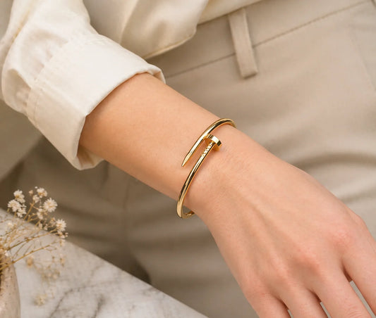Gold-tone cuff bracelet on wrist, slim open bangle with pointed ends
