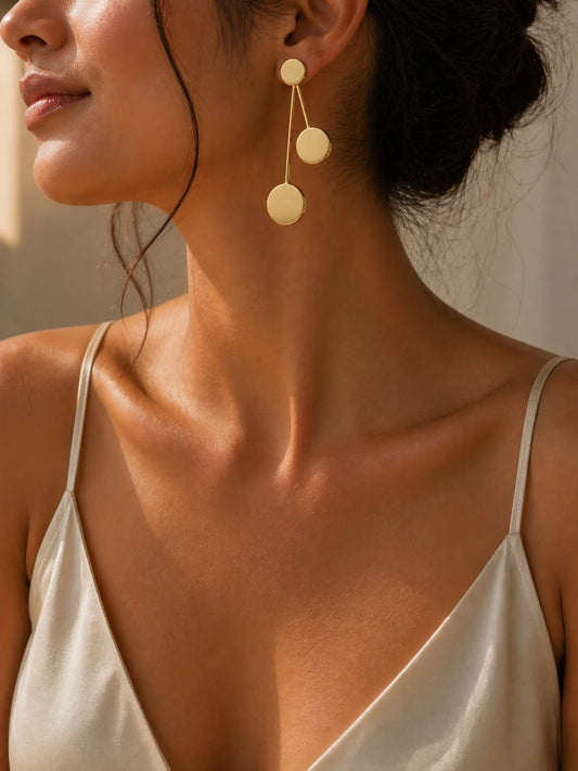 Gold-tone drop earrings with three dangling round discs on a thin wire