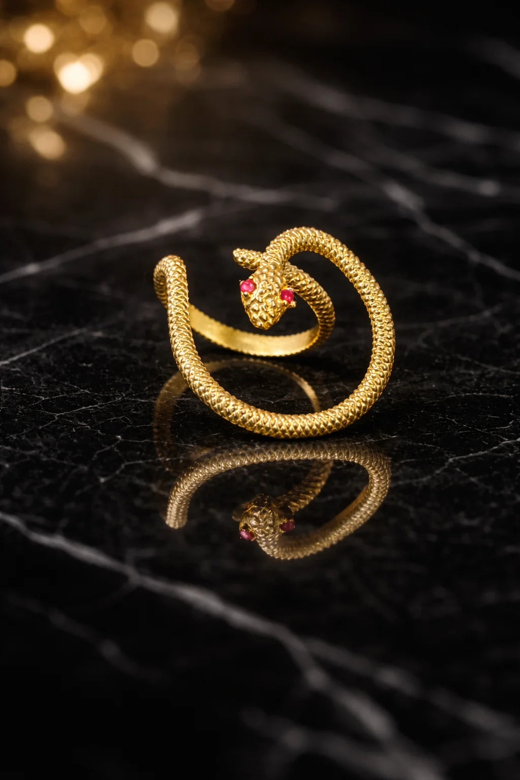 Gold-tone serpent statement ring with coiled band and red eyes