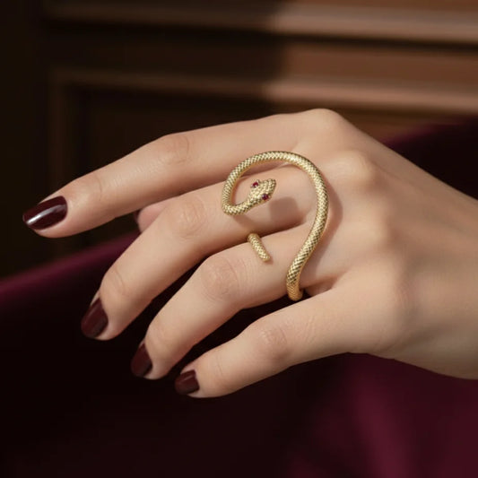 Gold-tone serpent ring on finger, coiled band with red-eyed head detail