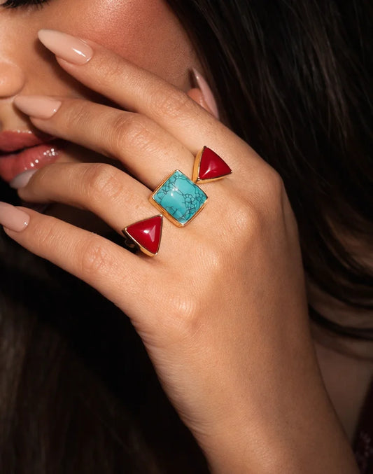 Turquoise square and red triangular statement ring on gold band, on finger