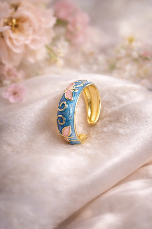 Blue enamel ring with gold edge, scrollwork and pink insets on a slim band