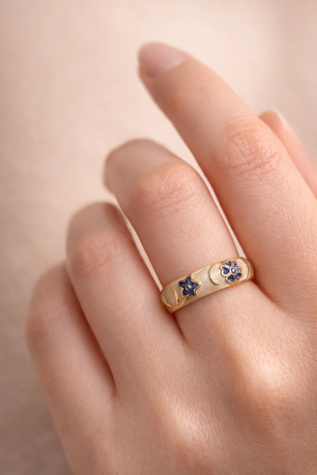 Gold-tone band ring on finger with blue star enamel detailing