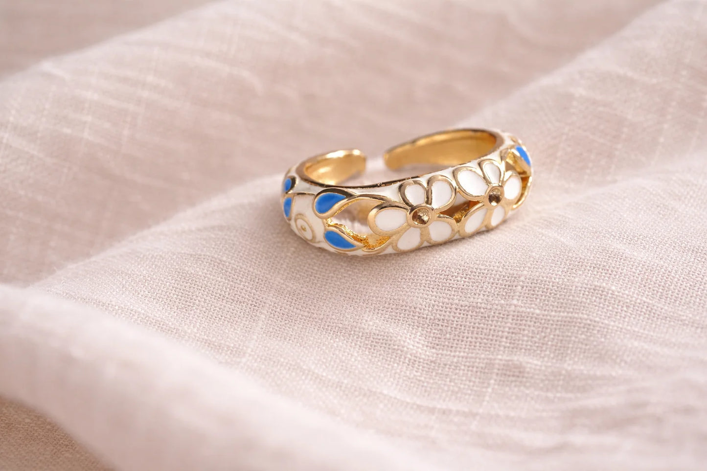 Gold-tone enamel ring with blue-and-white floral inlays and openwork swirl design