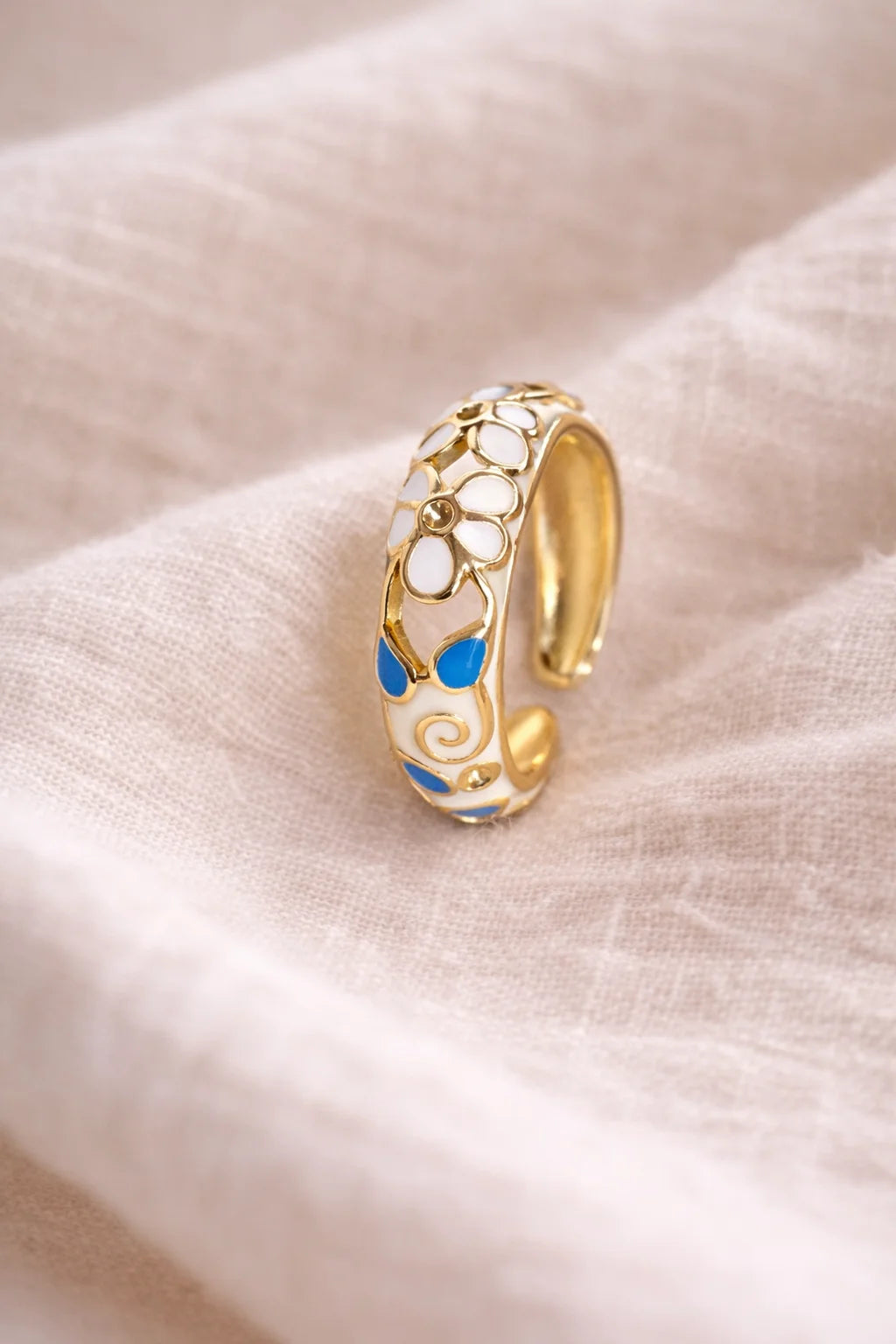Gold-tone enamel ring with blue floral accents and swirl cutouts, wide band
