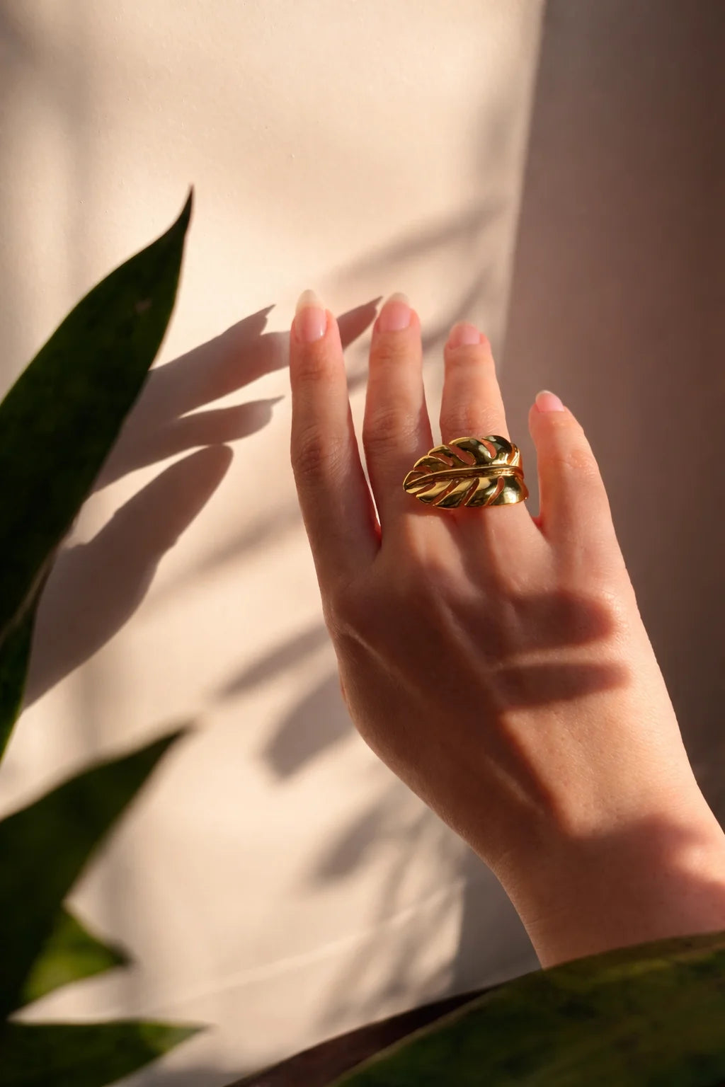 Gold-tone banana leaf ring on finger with curved leaf motif