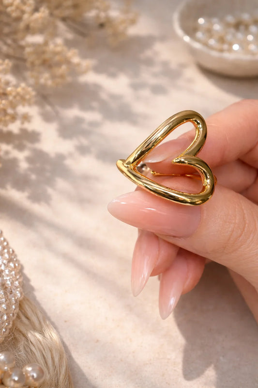 Gold heart-shaped doodle ring on finger, open outline with smooth edges