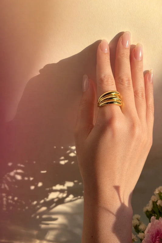 Four-layer gold ring on finger with stacked spiral bands and polished shine