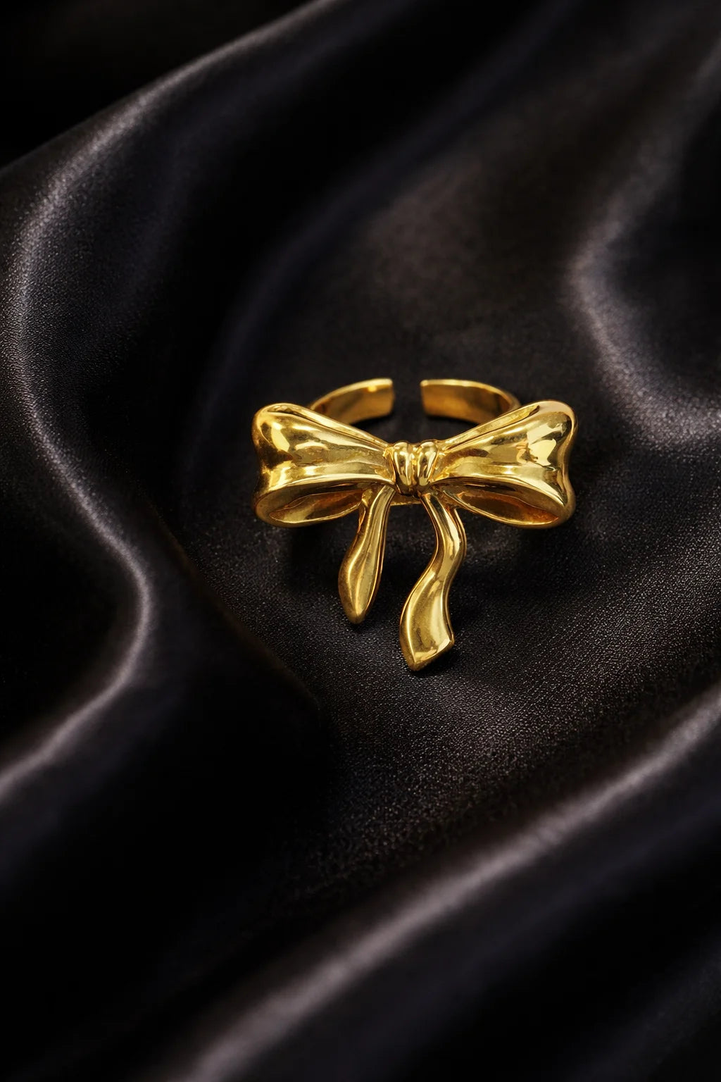 Gold-tone bow ring with sculpted ribbon bow and dangling ribbon ends, open band