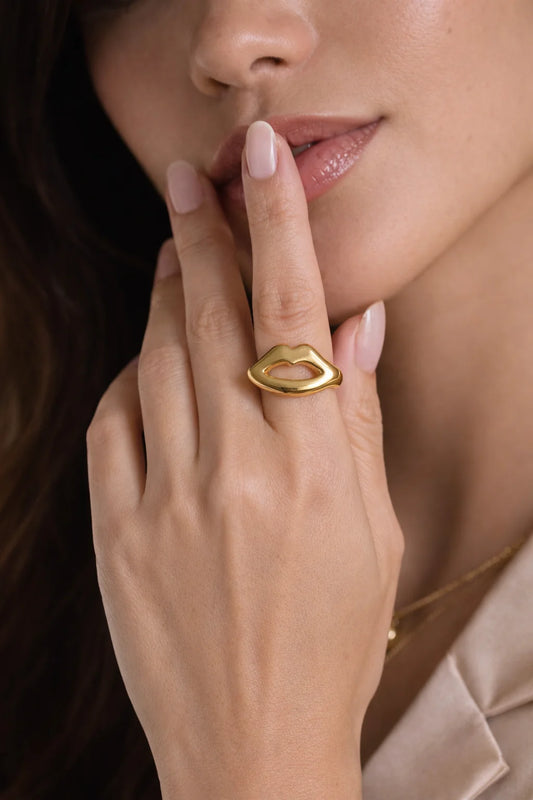 Gold-tone lip pout ring worn on finger, glossy open-mouth design
