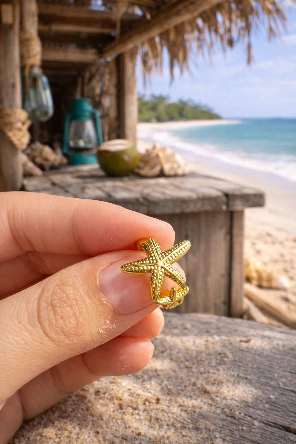 Starfish ring in gold-tone, worn on finger; detailed starfish charm on band.
