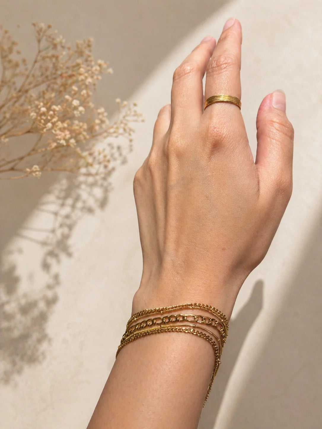 Stack bracelet on wrist: slim gold-toned chain with multiple layers and clasp