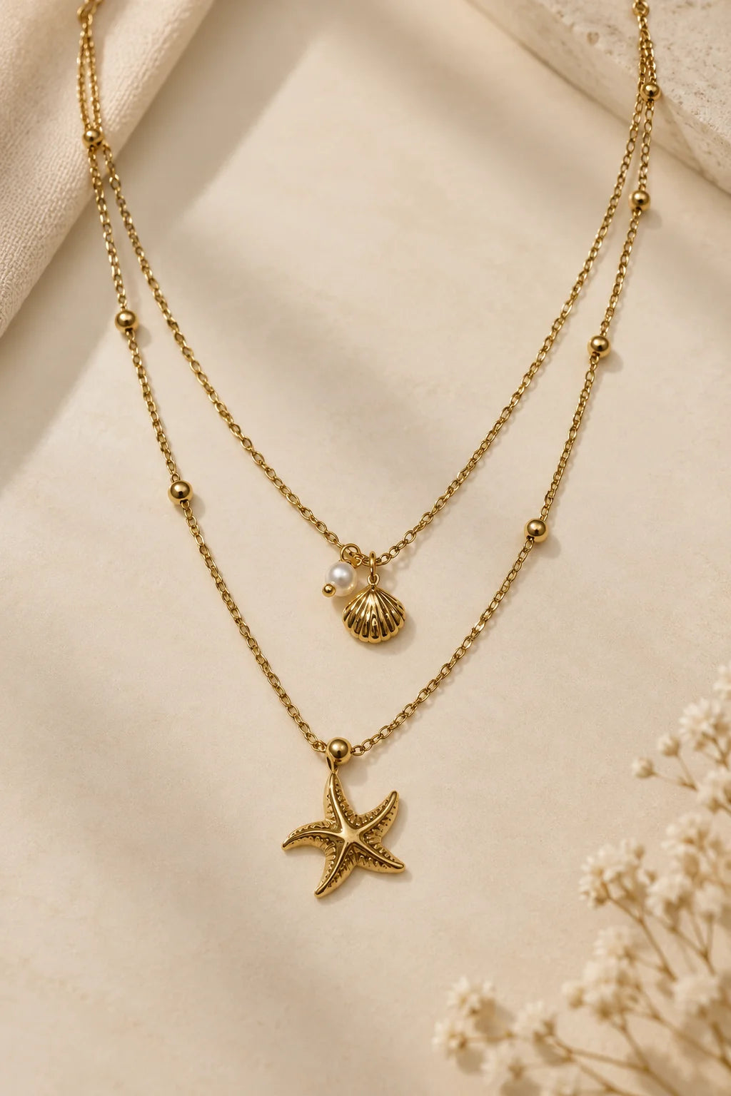 Gold-tone layered necklace with starfish, shell charm, and bead stations on chains
