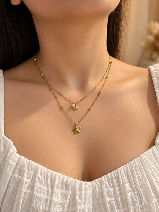 Gold-tone layered necklace with starfish and small shell charms on short chains