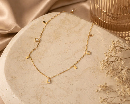 Gold square charm necklace with small square charms spaced along a fine chain