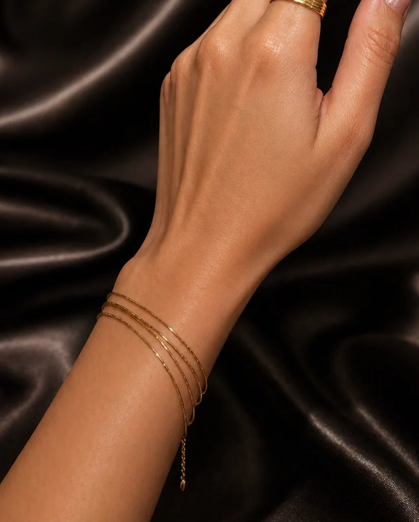Gold-plated stack bracelet with three thin chain strands on wrist, small clasp