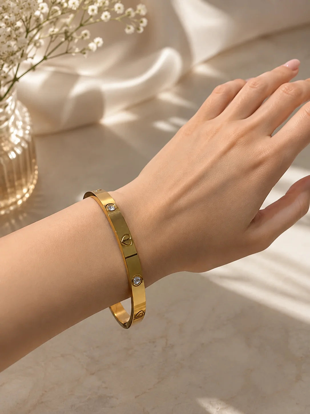 Gold-tone stainless steel kada bracelet with heart and crystal stones on wrist