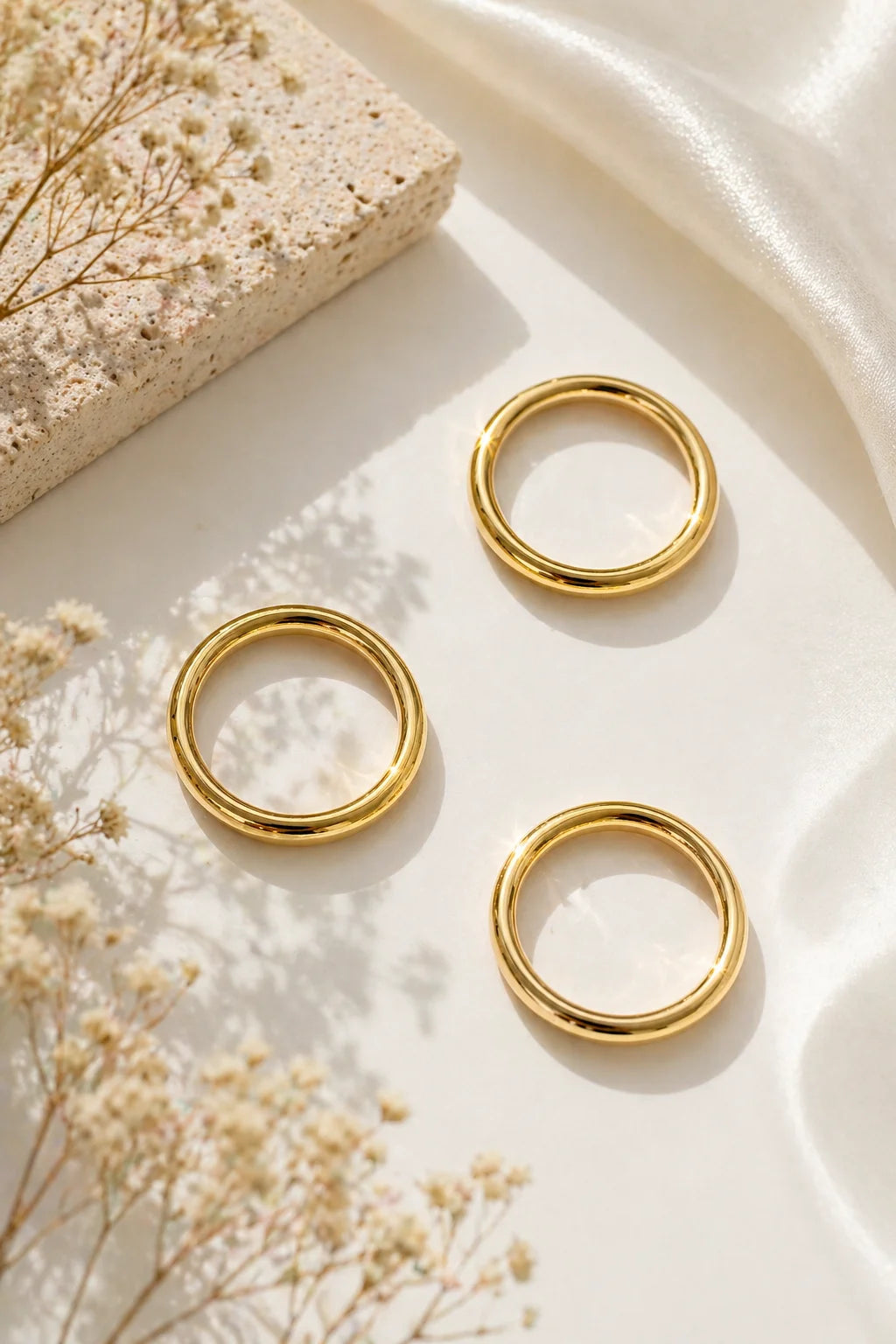 Gold-plated stackable rings, three thin bands on a light surface