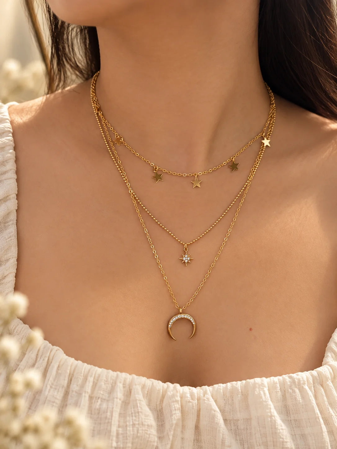 Gold layered necklace with star charms and crescent moon pendant on three chains
