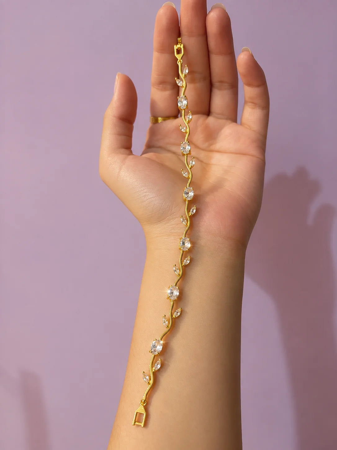 Gold-tone dangling bracelet with small clear rhinestones and clasp, shown in hand