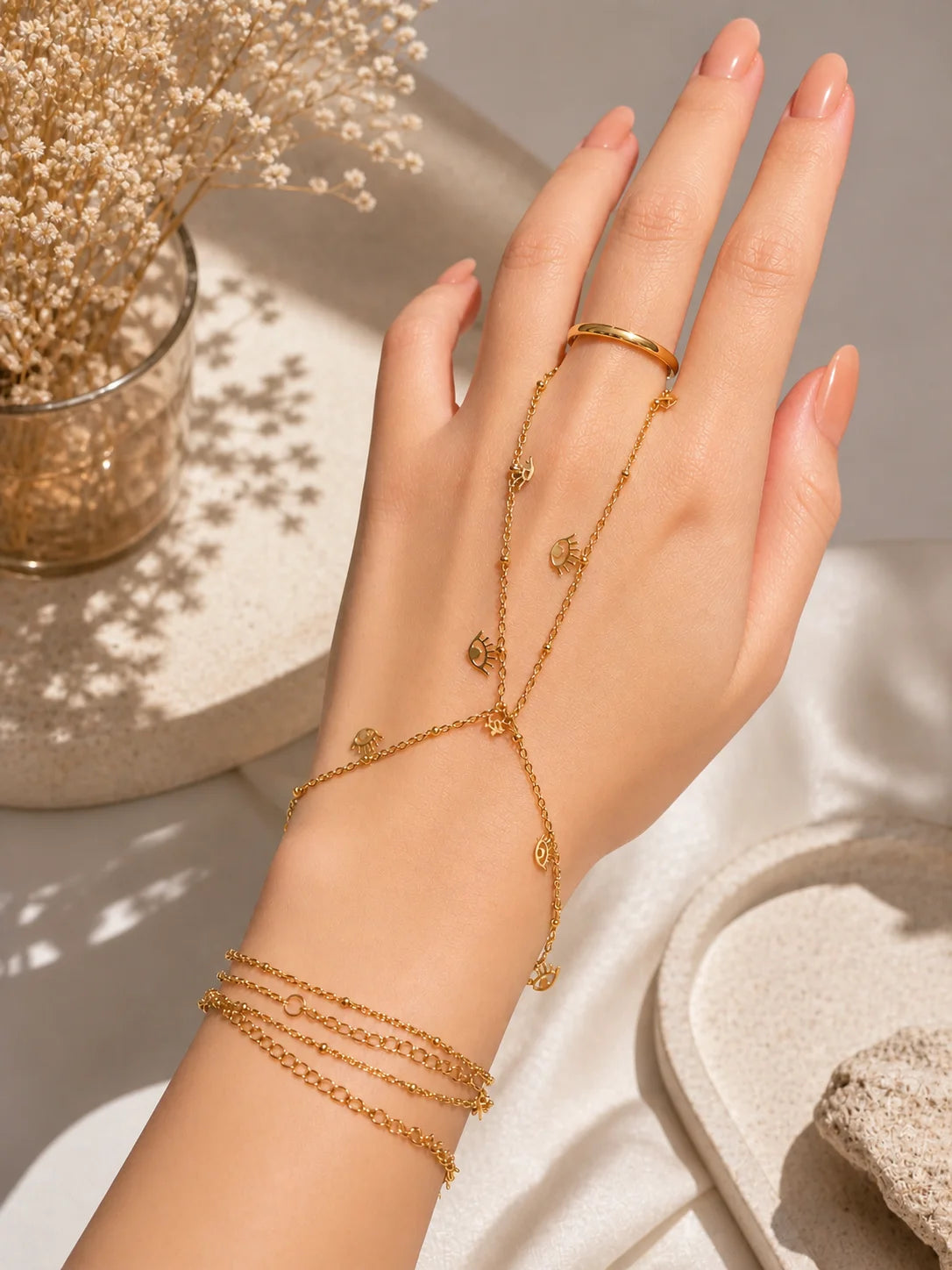 Gold-plated layered chain bracelets with charm pendants near the hand
