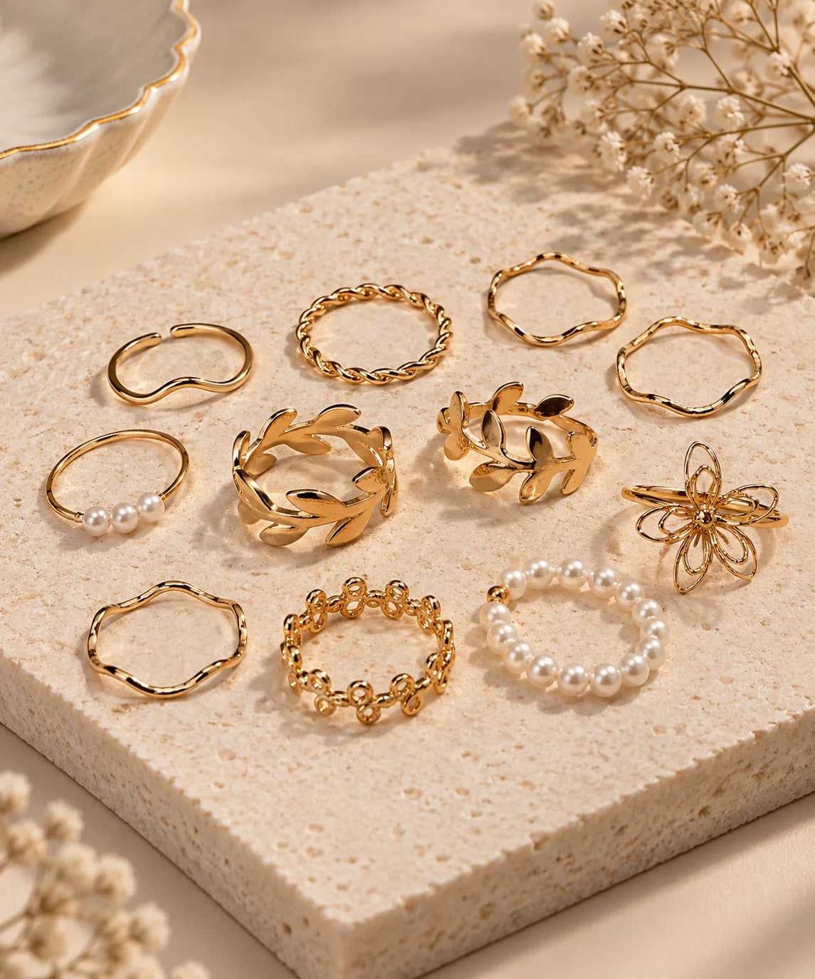 Assorted gold-tone adjustable rings with pearl accents, floral and chain styles on display