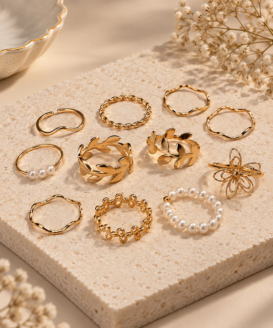 Assorted gold-tone adjustable rings with pearl accents, floral and chain styles on display