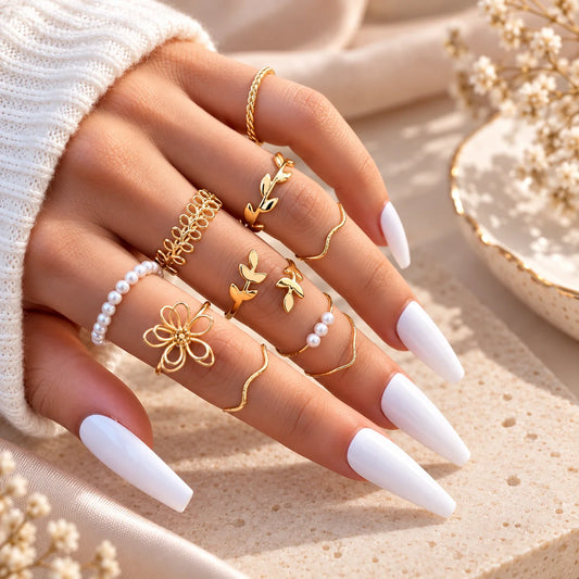 Gold-tone adjustable rings with white pearl beads and flower and leaf charms on fingers