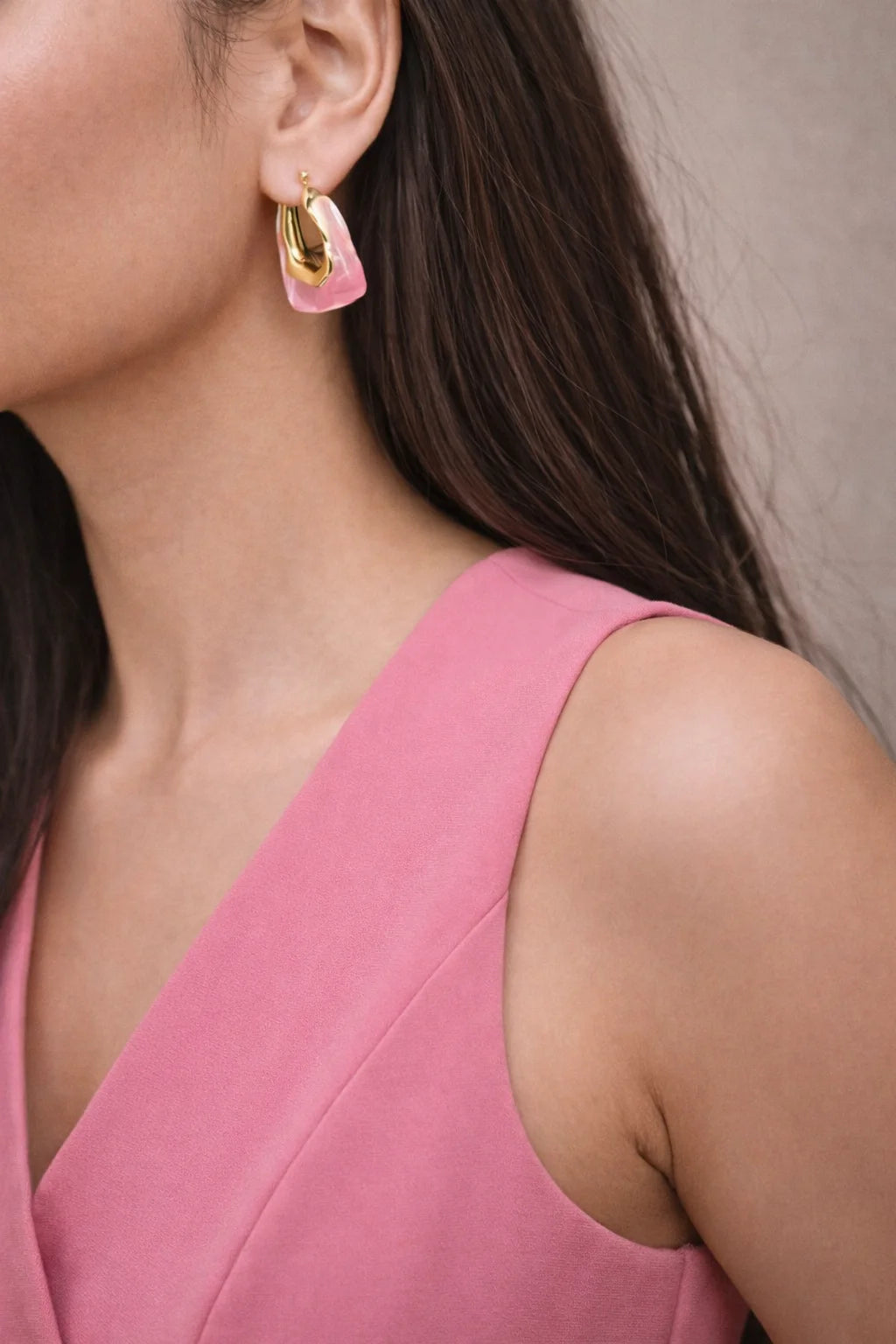 Pink and gold half-moon earrings on a model's ear, small hoop backing