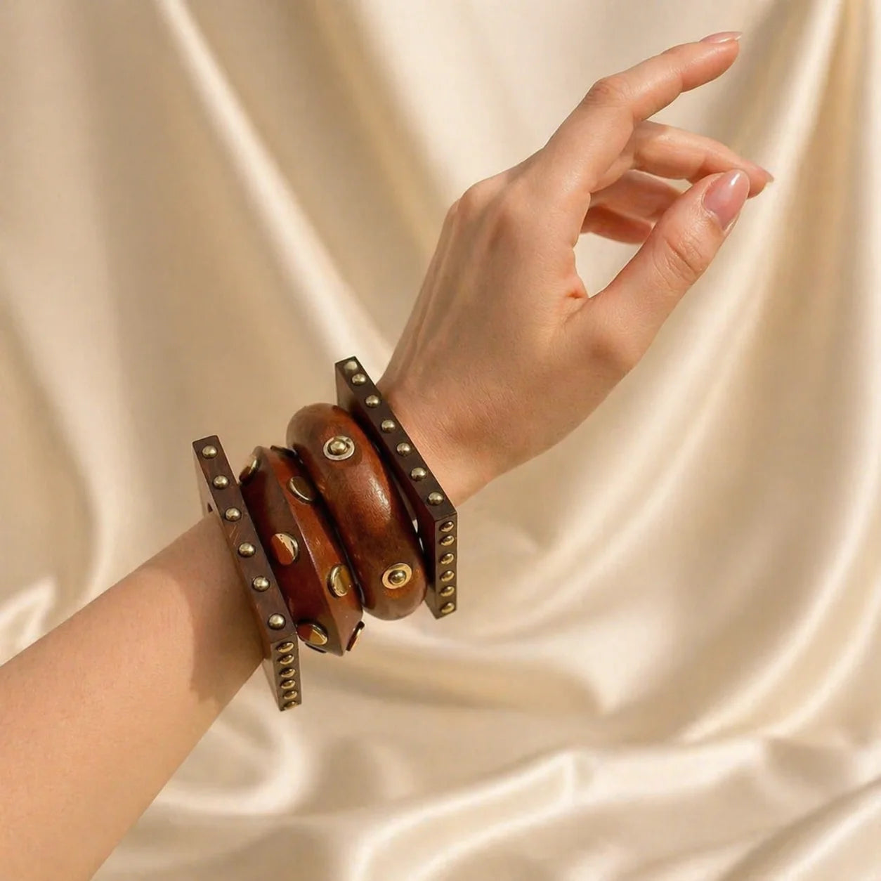 Wooden bangle with layered brown bands, gold rivets and studs on wrist