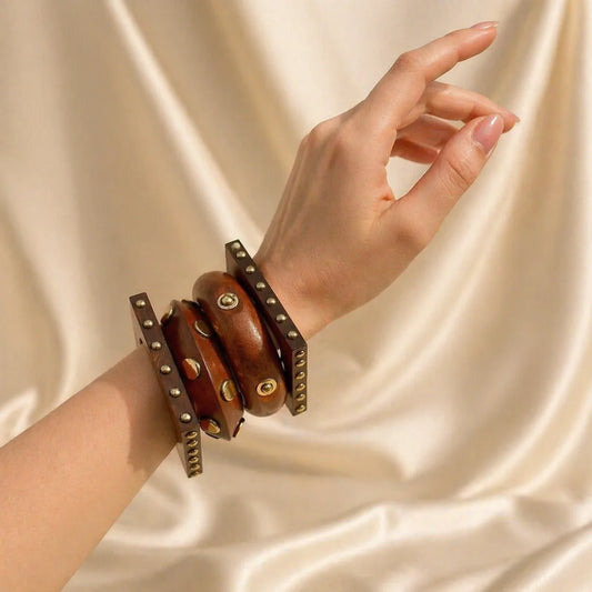 Wooden bangle with layered brown bands, gold rivets and studs on wrist